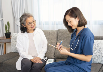A senior woman giving a health interview to a home visiting nurse, a young female taking a patient data notes on flip chart paper,concept of elderly health,homecare,home health nursing