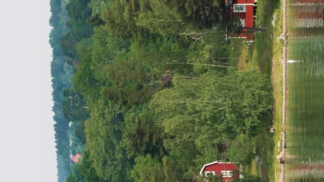 Red Scandic Wooden Houses On Island Coast In Summer Cloudy Day. Nordic Architecture. Vertical Footage Video Hyperlapse. Travel Concept To Sweden. Scandinavian Culture And Nature.