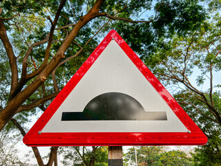 A red and white sign with a black triangle with speed breaker symbol
