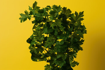 Green Leaves Forming Silhouette of Man's Head on Yellow Background, Nature and Human Connection Concept
