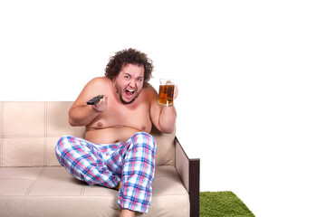 Fototapeta premium Funny fat man drinks beer and watches the match on TV.