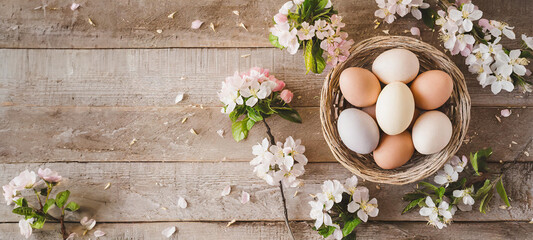 Easter eggs in a basket on a wooden table with spring flowers, cherry branch. Copy place. Top view. . Easter card and banner. Generative AI - 797917047