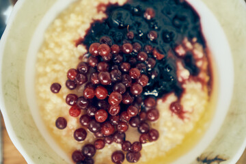 Warm wheat porridge with red currants and blueberry jam.A close-up of a plate of wheat porridge for a healthy gluten-free breakfast. High quality photo