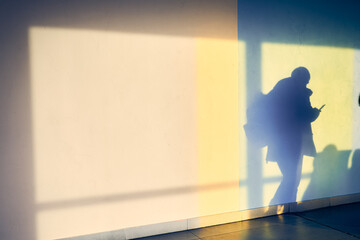 Abstract background of a man's shadow on a white wall at the airport with space to copy. Blurred silhouettes of people. High quality photo