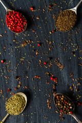 Old spoons with various seeds and spices on black background - obrazy, fototapety, plakaty