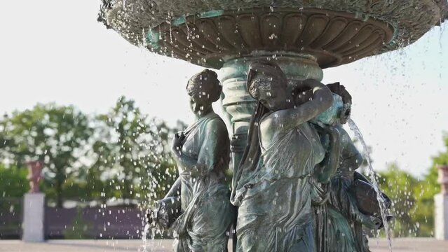 Large decorated fountain. Outdoor furniture, jets of water fall on the statues of baroque nymphs. Parallax scrolling, slow motion video.