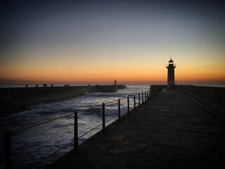 Sunset at the ocean pier with a Farol de Felgueiras lighthouse in Foz do Douro, Porto, Portugal,...