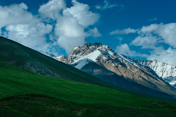 Picturesque valley with snow covered mountains and green meadow