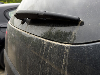 Saharan dust on a grey black car. Close up photo of a car covered with duster after an African...