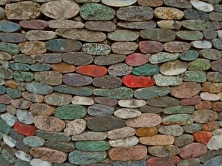 Cut pebble stone texture wall or floor colorful background. Fence made from gravel different round...