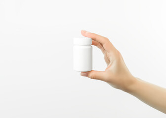 hand holding a white plastic jar with pills on a white background