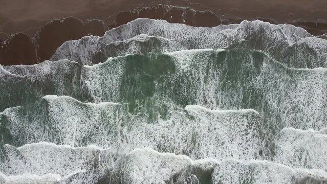 Overhead video of waves breaking on the beach.
