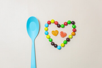 Heart shaped Candy and multi colored candy and blue spoon on Isolated on White Background.