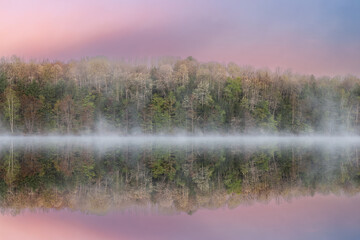Fototapeta na wymiar Foggy spring landscape at dawn of Moccasin Lake with mirrored reflections in calm water, Hiawatha National Forest, Michigan's Upper Peninsula, USA