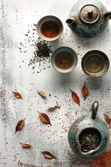 Teapot with cups, bowl of dry tea and leaves on white grunge background - obrazy, fototapety, plakaty