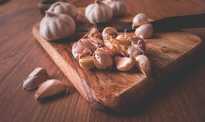 fresh garlic on a chopping board, wooden table, knife, rustic, mobile photo, no people,