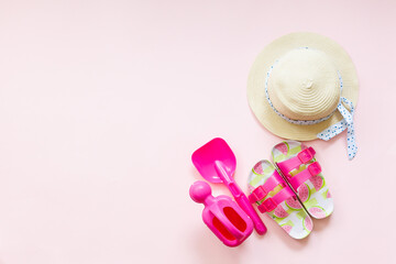 beach accessories on a pink background. Things for a child at sea: flip flops, a shovel for sand...