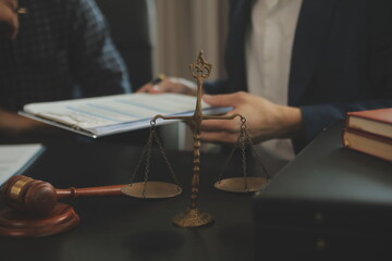 Justice and Law concept. Legal counsel presents to the client a signed contract with gavel and legal law or legal having team meeting at law firm in background