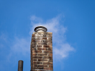 steam and smoke coming from a brick chimney with gas liner on a cold clear day