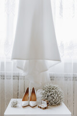 A pair of white shoes and a bouquet of white flowers are displayed on a table