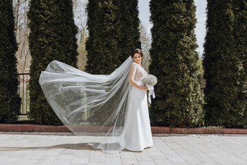 A woman in a white dress is standing in front of a hedge