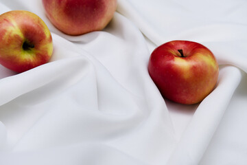 Apples placed on beautiful white fabric. Close-up red apple concept as a healthy gift, and fresh...