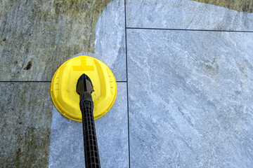 Pressure jet washer being used to clean porcelain tiles on a garden patio showing the difference before and after cleaning