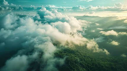Fototapeta premium A breathtaking aerial view of a lush mountain landscape partially enveloped in mist and low clouds. Sunlight filters through the clouds, illuminating the rolling hills and valleys with a warm, golden 