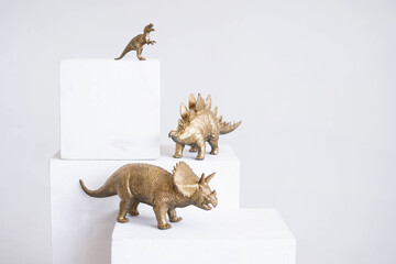 Golden dinosaur figurines on a white background.