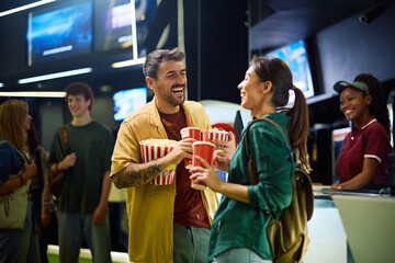 Cheerful couple having fun before movie projection in cinema.