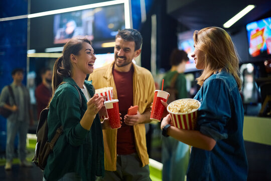 Cheerful woman having fun with her friends before projection in movie theater.