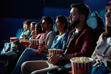 Group of people watching suspenseful in cinema.