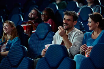 Happy man enjoying in film projection with his girlfriend at cinema.