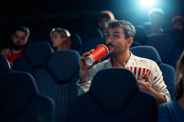 Smiling man enjoying in movie projection in cinema.