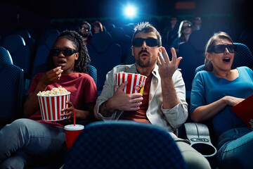 Shocked spectators watching 3D movie in cinema.