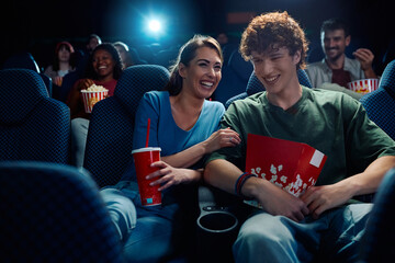 Cheerful couple enjoying in film screening in movie theater.
