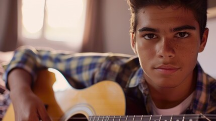 The close up picture of the hispanic male child playing or practicing guitar inside his own room,...
