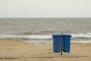 blue garbage cans on the sandy beach