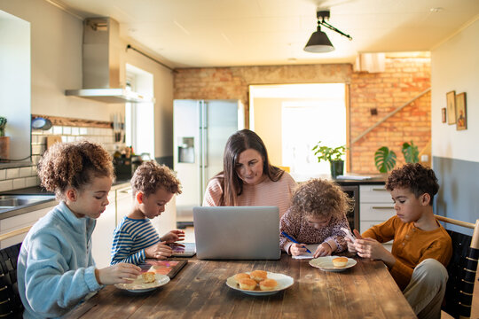 Mother multitasking with work and children during breakfast at home