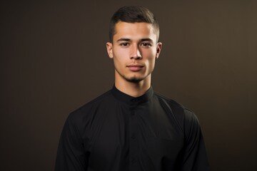 Obraz premium A man in a black shirt is standing in front of a brown background
