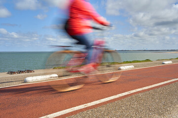 Blur. Cycling in Holland. Leisure activity at a kite spot. Woman blur on bicycle. Netherlands,...
