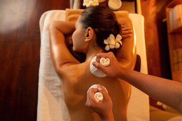 Top view hot herbal ball spa massage body treatment, masseur gently compress herb bag on woman...