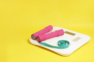 Scales, meter, dumbbells on a yellow background