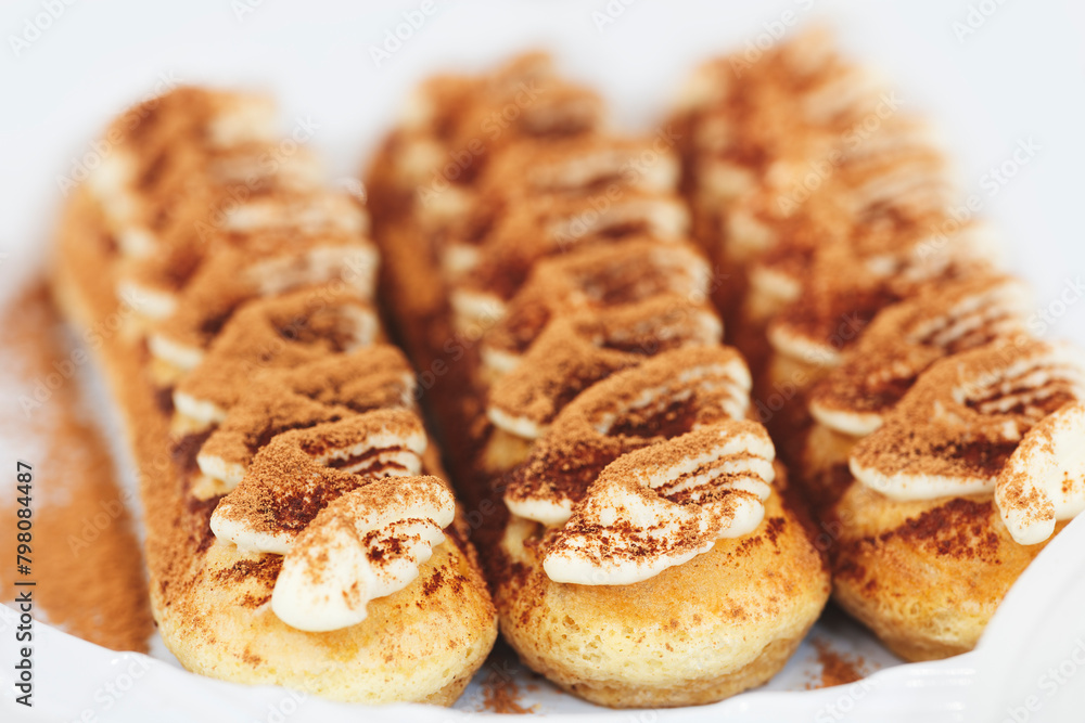 Poster three brown pastries with white frosting and sprinkles. the pastries are arranged in a row on a whit