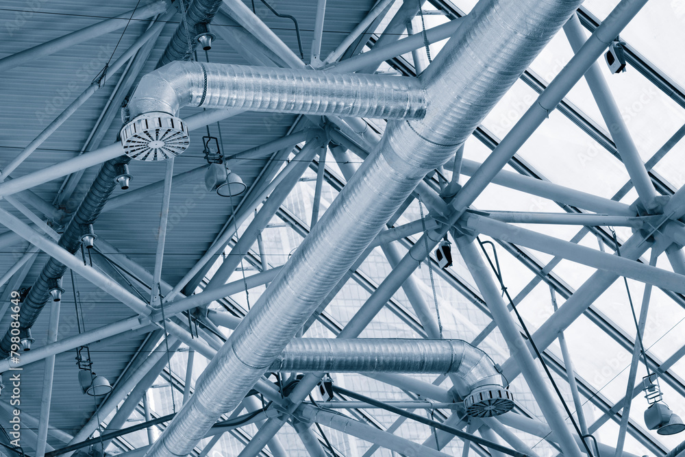 Poster a large building with a lot of metal beams and a lot of light. the beams are silver and the building