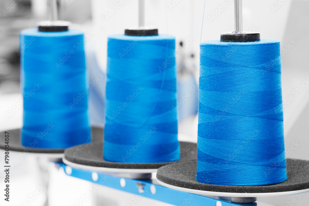 Aufkleber spools of blue color threads closeup, spinning machine