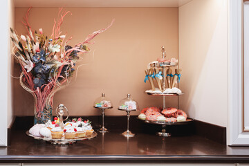 A table with a vase of flowers and a variety of desserts, including cupcakes and donuts