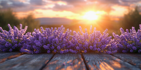 Vibrant lavender flowers on a wooden surface with a sunset over a mountainous horizon in the background.