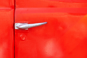 Door handle of a retro car close-up. metal lock, door painted red