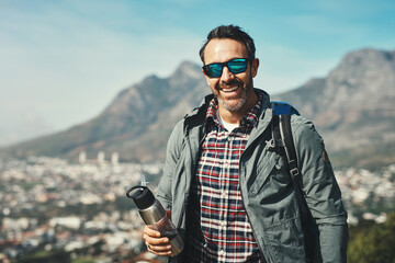 Man, portrait and mountain travel with adventure gear, smile and eco vacation with walking trail....